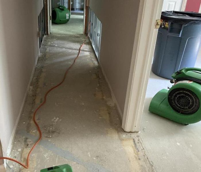 Basement hallway with carpet removed and SERVPRO machines.